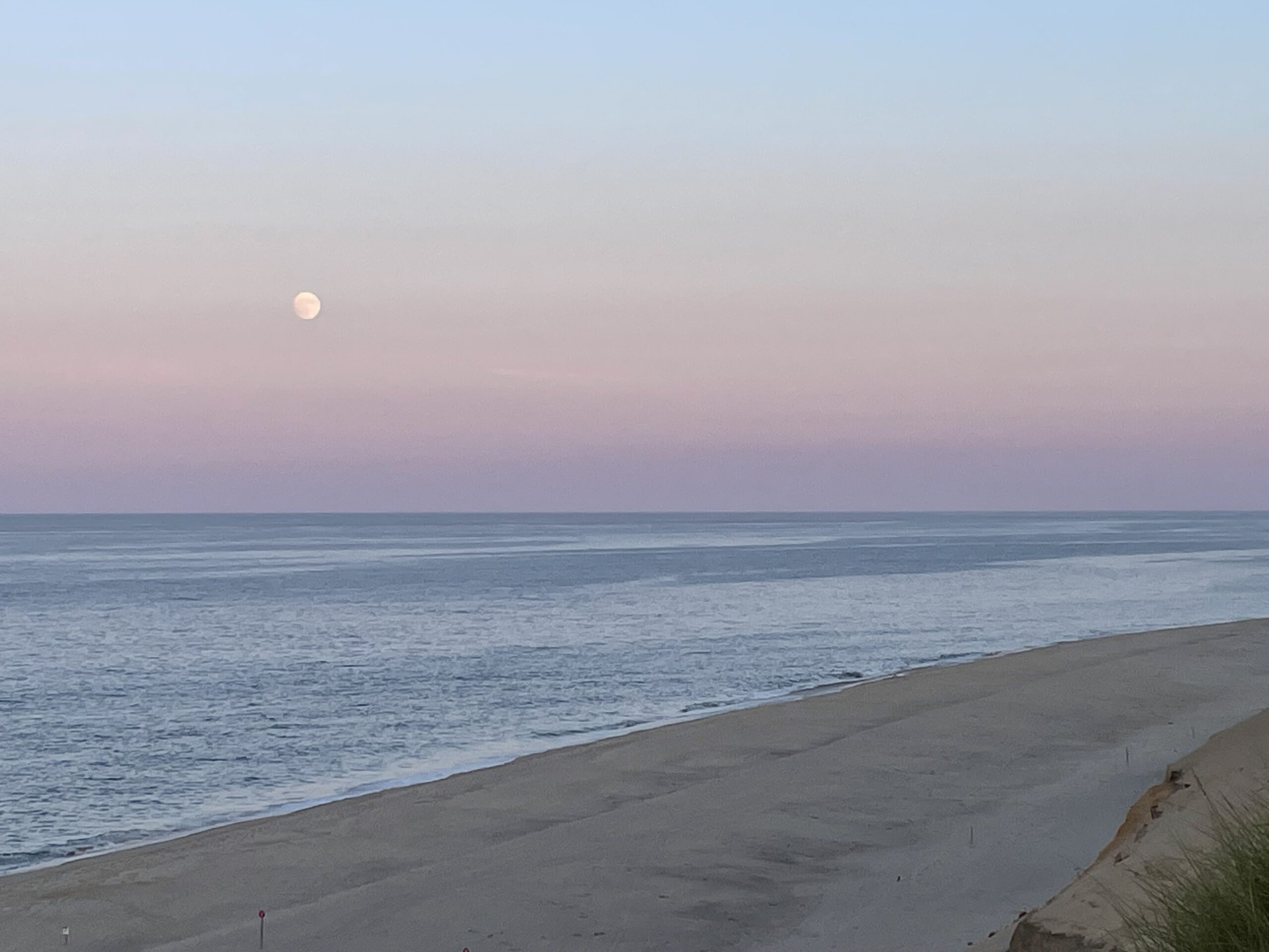 Photograph of a moon rising over the Atlantic Ocean at Lecount Hollow Beach in Wellfleet, Massachusetts.