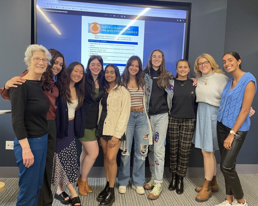 Author, far left, with nine students in front of a large screen reading "2023 ILA Symposium Presentation Schedule."